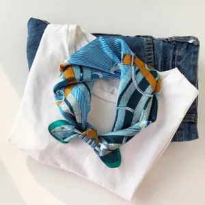 Nahaufnahme eines eleganten blau-gelben Seidentuchs auf weißem T-Shirt und Jeans.