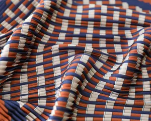 Pleated silk scarf fabric detail close up geometric pattern soft texture orange and navy blue.