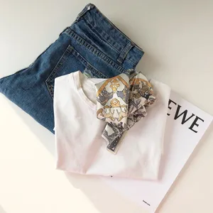 Vue détaillée à plat d'un élégant foulard en soie stylisé avec un t-shirt et un jean.