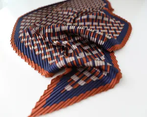 Detailed close-up of a pleated satin square scarf with elegant blue and orange print.