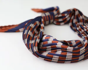 Detailed view of women's pleated faux silk scarf featuring a geometric grid pattern.