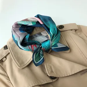 Dettaglio ravvicinato di foulard in seta con stampa artistica ad olio annodato sul colletto.