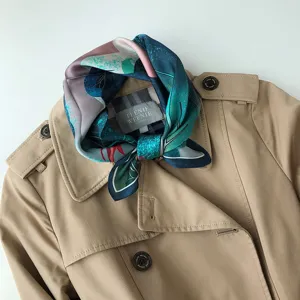 Elegante sciarpa in seta con stampa artistica, abbinata ad un classico trench coat.