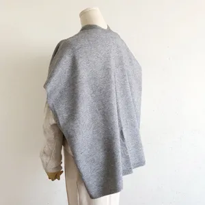 Gedetailleerd overzicht van de zachte grijze gebreide poncho met de achterkant en winterstijl.