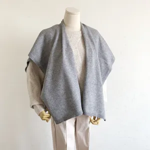 Grijs gebreide cape detail toont zachte woltextuur en elegante drapering voor de winter.