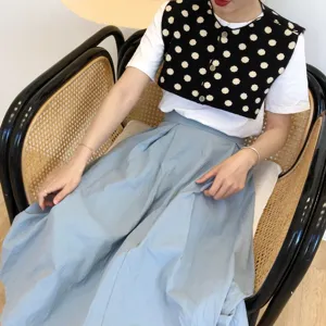 Women stylish polka dot vest white t-shirt and light blue long skirt fashion outfit detail.