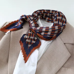 Detailed view of the pleated geometric print silk scarf tied neatly over a stylish shirt.