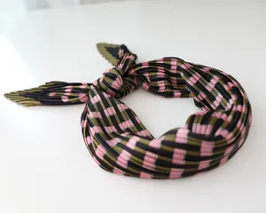 Detailed view of the pleated silk-feeling scarf featuring a stylish pink, green and black checkered pattern.