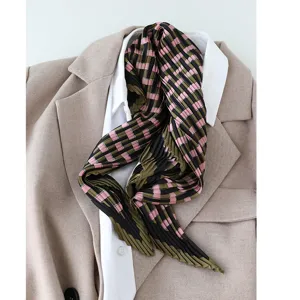 Detail view of a stylish pleated faux silk scarf featuring a chic black green and pink grid pattern.