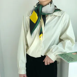 Primer plano del pañuelo de seda en el cuello de una modelo, mostrando un diseño colorido.