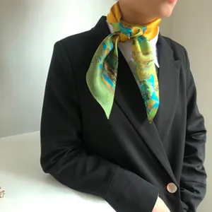 Close-up detail of the silk scarf featuring artistic yellow and green landscape print.
