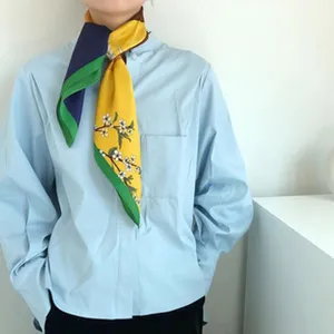 Detailed view of a stylish color-blocked silk scarf with elegant floral branch print.
