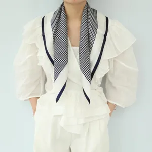 Detail view of stylish black and white silk neck scarf with chic navy border lines.