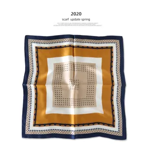 Detail shot of the geometric square silk scarf, showcasing elegant blue and gold pattern.