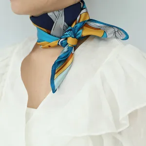 Detailed shot of a stylish silk square scarf with blue and yellow print worn on the neck.