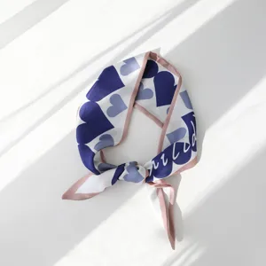 Dettaglio di foulard in seta con stampa cuore blu, elegante fazzoletto da collo.