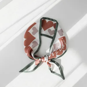 Vista dettagliata di un elegante foulard in seta con motivo a cuori e bordo verde.