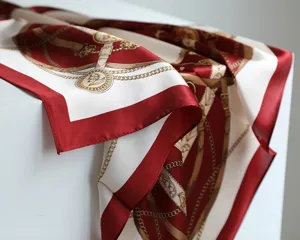 Vista di dettaglio del foulard in seta rosso vino con stampa classica a catena e cintura, raso liscio.