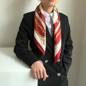 Dettaglio di un foulard di seta bordeaux con stampa elegante di catene e cinture.