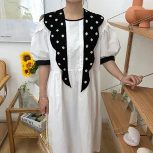 Detailed view of the white puff sleeve dress featuring a stylish black polka dot shawl collar.