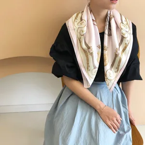 Detailed view of a pink silk scarf featuring vintage carriage and belt print for elegant look.