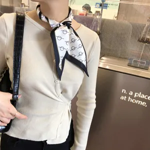 Foulard skinny en soie à imprimé géométrique noir et blanc élégamment noué au cou.