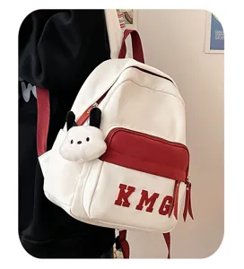Detalle de la mochila escolar blanca y roja con un peluche tierno para los ninos.