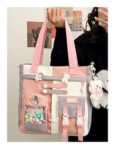 Vue détaillée du sac cabas en toile colorblock rose avec breloques et poches multiples.