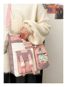 Gros plan sur le sac bandoulière en toile rose avec poche transparente et écusson d'astronaute.
