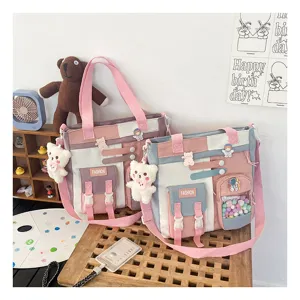 Vue détaillée du sac cabas en toile mignon, design colorblock avec charm peluche d'ours et poches.