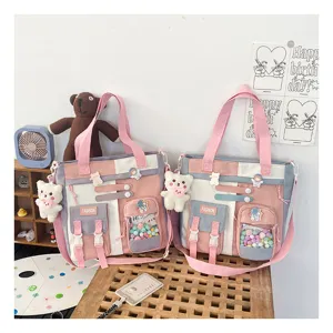 Sac cabas bandoulière en toile multi-poches avec joli pendentif ours et compartiment transparent.