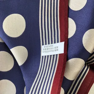 Seidenschal-Detailansicht mit Polka-Dot-Muster, gestreiftem Rand und dem Seidenetikett.