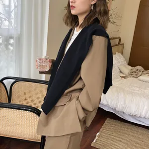 Nahaufnahme des stylischen Strickschals kombiniert mit einem klassischen Blazer im gemütlichen Raum.