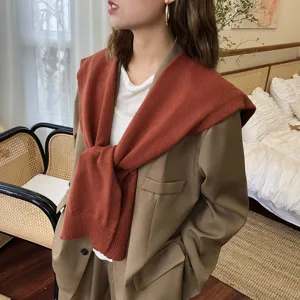 Detailansicht eines stilvollen rostbraunen Strickschals über khakifarbenem Blazer, Herbst.