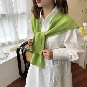 Detailansicht eines stylischen grünen Strickschals, gebunden über einem weißen Hemd.