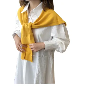 Stilvoller gelber Strickschal als Schulterumhang kombiniert mit einem weißen Hemd.