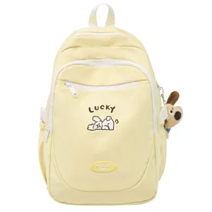 Detail view of the yellow student backpack, featuring front pocket and cute puppy doll ornament.