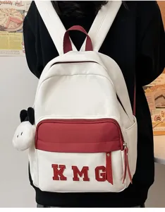 Linda mochila escolar blanca y roja con letras KMG y colgante de peluche para niños.