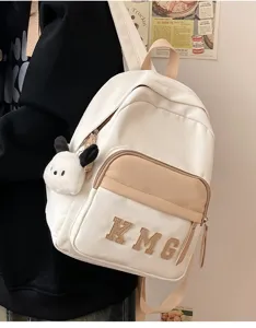 Primer plano detallado de una bonita mochila de lona blanca y caqui con colgante de felpa.