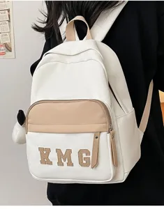 Vista detallada de la mochila infantil blanca y kaki con bolsillo delantero y dije.