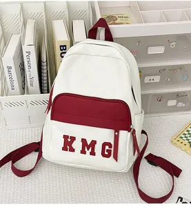 Vista detallada de una mochila casual blanca y burdeos con bordado KMG en el escritorio.