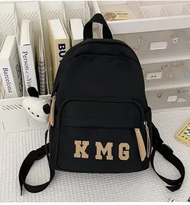 Mochila escolar negra para niños con parche de letras y colgante, ligera para viajes y diario.