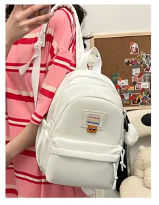 Zaino piccolo bianco da donna, borsa studentesca alla moda con ciondolo peloso e patch.