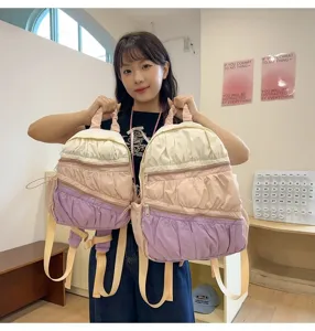 Dettaglio dello zaino pieghettato multistrato con tasche con zip e graziosa sfumatura di colore.