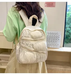 Dettaglio del mini zaino plissettato bianco con tasche multiple con zip e tessuto morbido.