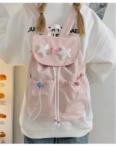 Close up detail of cute pink canvas backpack featuring plush star decorations and handy pockets.