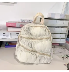 Dettaglio di uno zaino beige con volant arricciati, che mostra un design trapuntato unico.