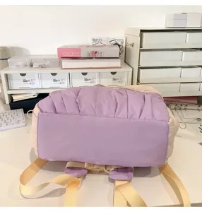 Primo piano dettagliato del mini zaino plissettato viola e beige con strati fini.