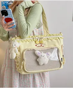 Yellow ruffled ita bag detail with clear mesh window, cute plush pendants, and delicate embroidery.