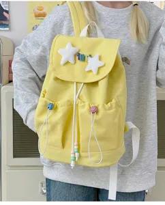 Detail view of a cute Japanese style yellow canvas backpack featuring plush star decorations and pockets.